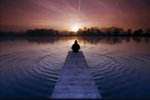 uomo seduto in riva al lago